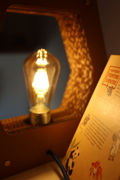 Lampe hexagonale Promis diffusant une lumière douce et chaleureuse.
